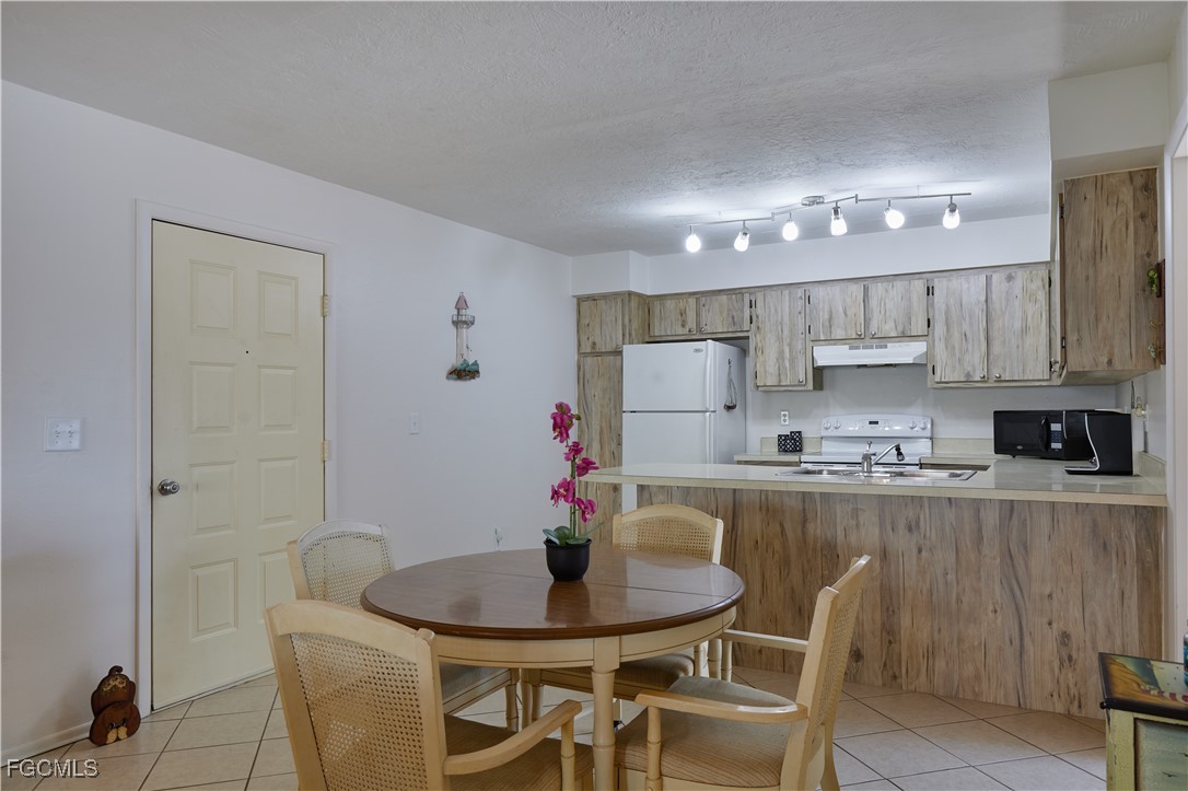 1100 Pondella Road, Unit 801 Cape Coral, FL 33909 - Photo 11 of 24 a kitchen with kitchen island a dining table chairs cabinets and stainless steel appliances