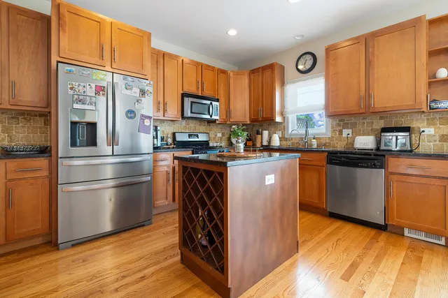 a kitchen with stainless steel appliances granite countertop a stove a sink dishwasher a microwave oven and a refrigerator