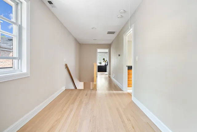 a view of a hallway with wooden floor and staircase
