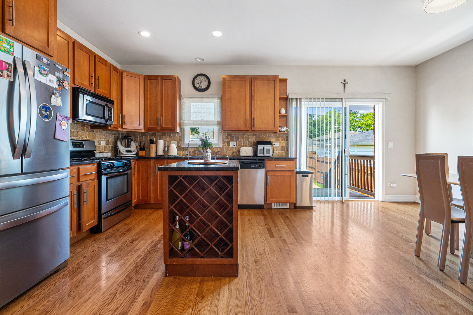 3638 North Odell Avenue Chicago, IL 60634 - Photo 10 of 46 a kitchen with stainless steel appliances granite countertop wooden floors stove top oven with a dining table and chairs