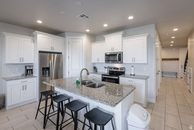 4845 Fishers Is Way St. George, UT 84770 - Photo 17 of 41 Kitchen with stainless steel appliances, light stone counters, white cabinetry, a kitchen bar, and recessed lighting