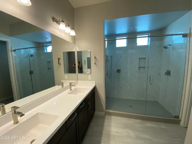 a bathroom with a double vanity sink mirror and shower