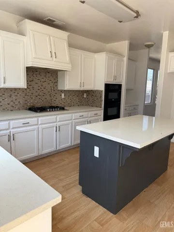 a kitchen with stainless steel appliances granite countertop a stove top oven a sink dishwasher and a refrigerator with wooden floor