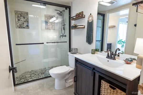 a bathroom with a sink a toilet a mirror and shower