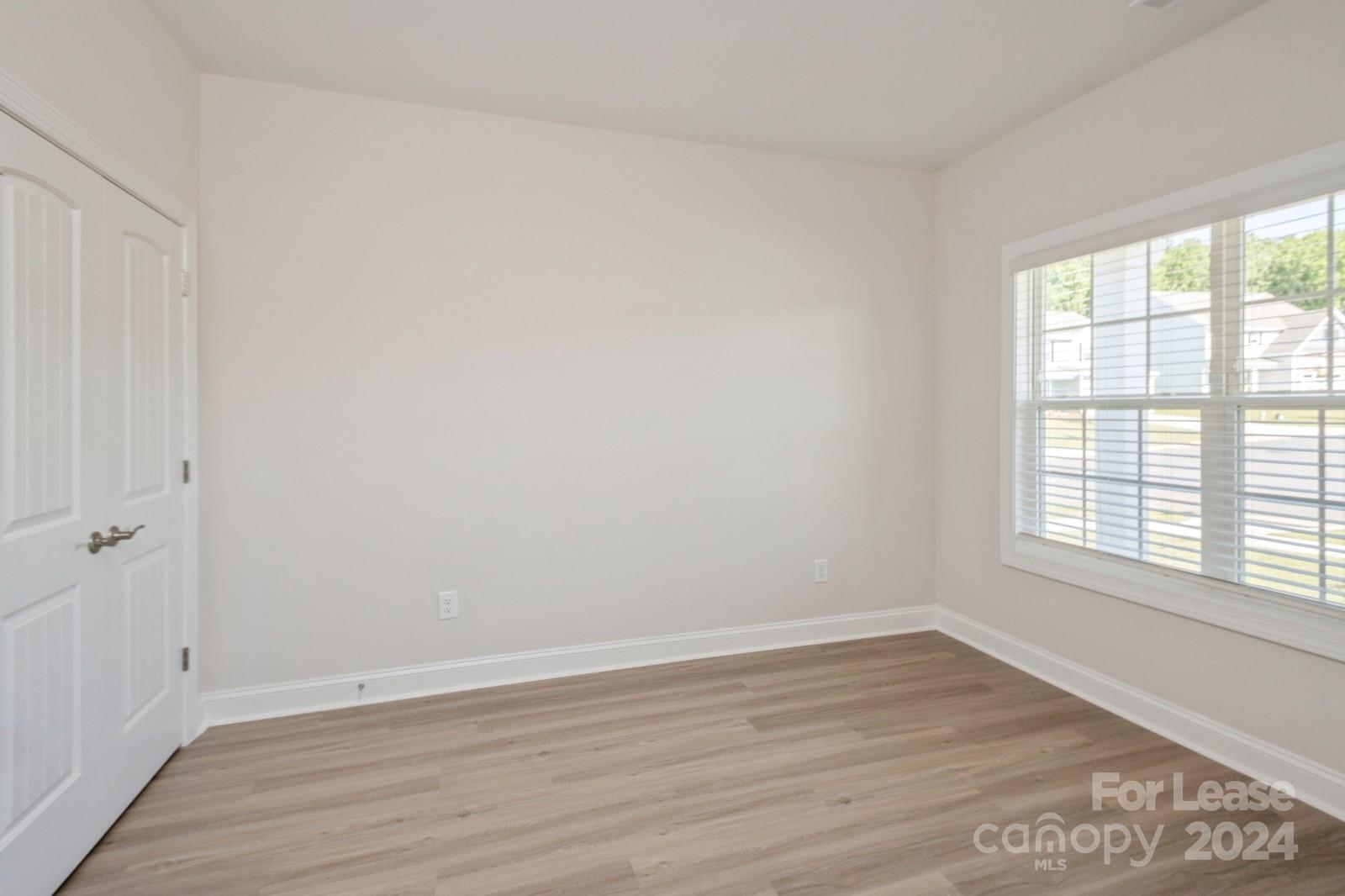 211 Adams Tree Way Troutman, NC 28166 - Photo 11 of 32 wooden floor in an empty room with a window