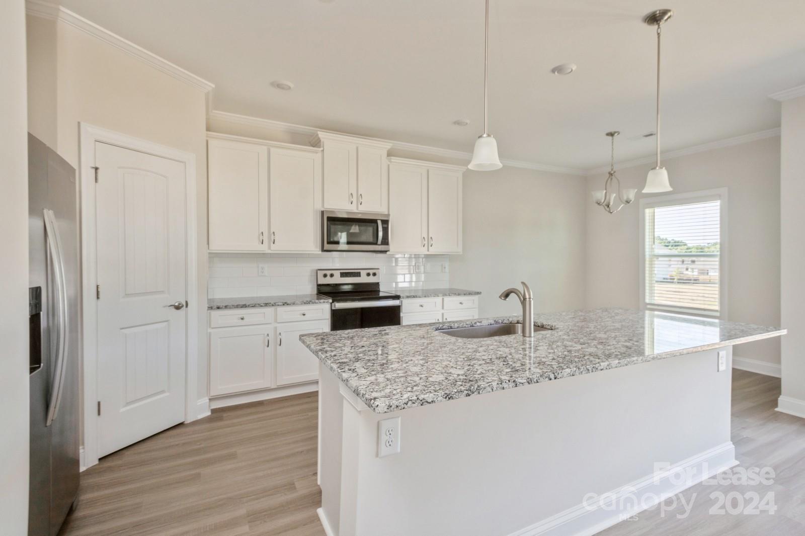 211 Adams Tree Way Troutman, NC 28166 - Photo 6 of 32 a kitchen with kitchen island granite countertop appliances cabinets a sink and a counter top space