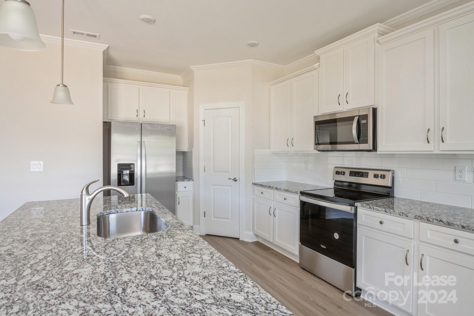 211 Adams Tree Way Troutman, NC 28166 - Photo 7 of 32 a kitchen with granite countertop a sink a stove and refrigerator