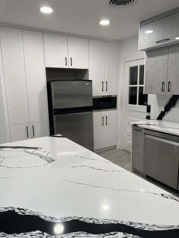 a kitchen with stainless steel appliances kitchen island granite countertop a sink stove and refrigerator