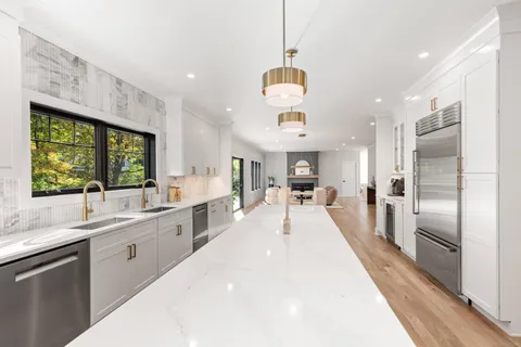 a large kitchen with kitchen island a large counter space a sink appliances and a window