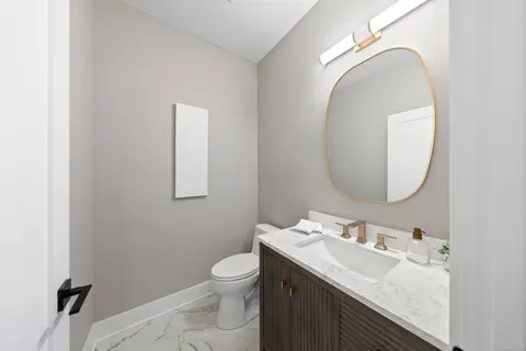 a bathroom with a granite countertop toilet a sink and mirror