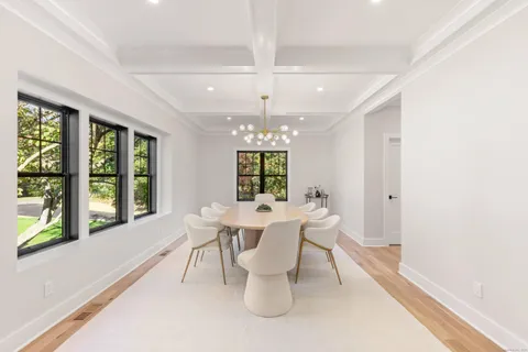 a dining room with wooden floor a chandelier a wooden table and chairs