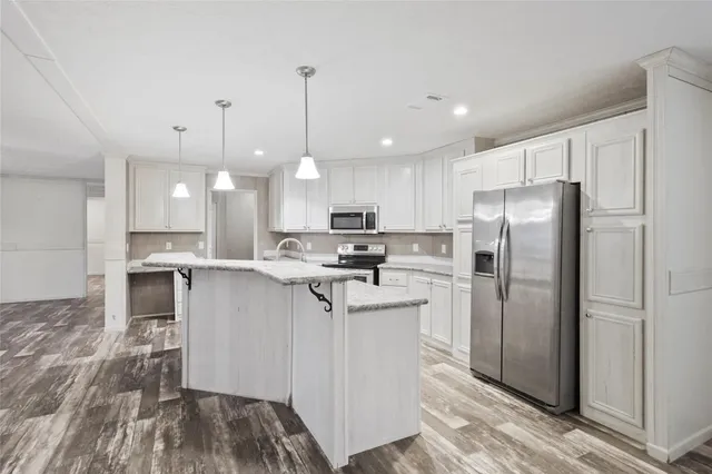 a kitchen with stainless steel appliances granite countertop a refrigerator a sink a stove and a oven