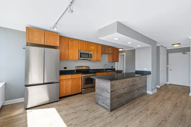 a kitchen with stainless steel appliances granite countertop a refrigerator a stove a sink and a refrigerator