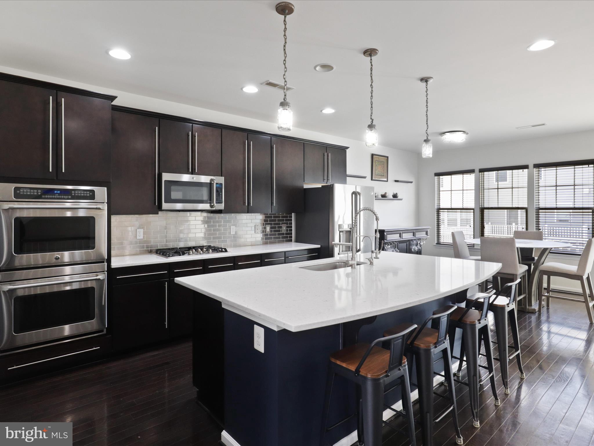 44021 Eastgate View Drive Chantilly, VA 20152 - Photo 10 of 30 a large kitchen with kitchen island a stove a table a sink and a refrigerator