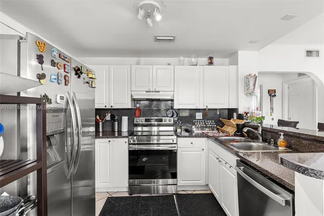 a kitchen with stainless steel appliances a stove sink refrigerator and cabinets