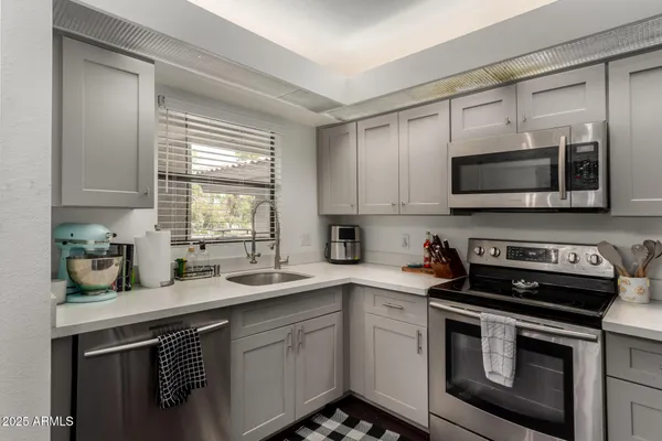 a kitchen with stainless steel appliances granite countertop a sink dishwasher a stove and a microwave oven with cabinets