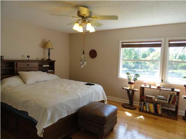 5573 Ponte Verde Road Pensacola, FL 32507 - Photo 15 of 24 The master bedroom with large windows overlooking the pool and hardwood floor