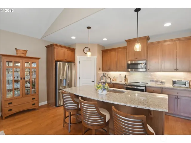 a kitchen with stainless steel appliances granite countertop a sink a stove and a refrigerator