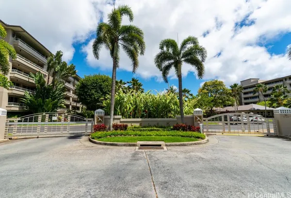 a palm tree sitting in front of a house with a garden