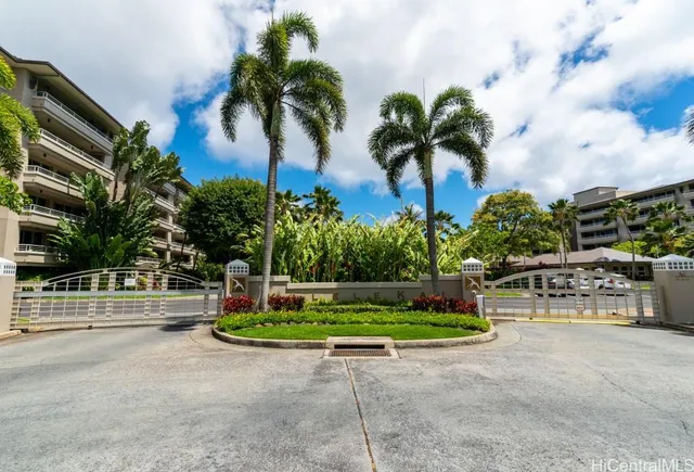 a palm tree sitting in front of a house with a garden