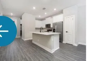 a large kitchen with stainless steel appliances a large counter top a stove a sink dishwasher and a refrigerator with wooden floor