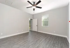 an empty room with wooden floor and ceiling fan