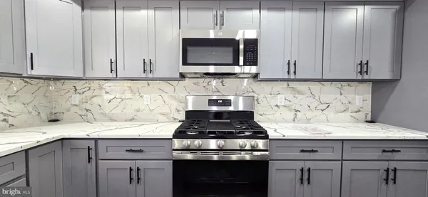a kitchen with granite countertop white cabinets and stainless steel appliances