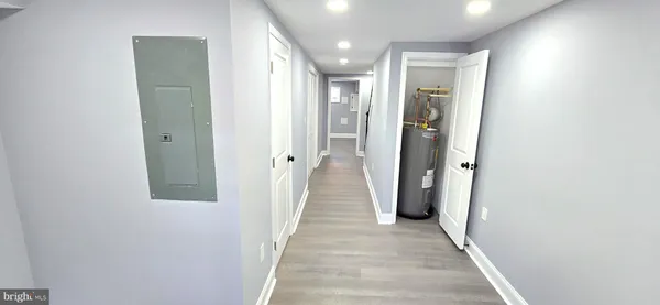 a view of a hallway with wooden floor and a bathroom