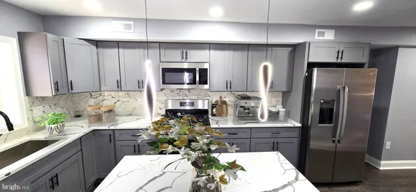 a kitchen with stainless steel appliances a refrigerator a sink a stove a microwave a counter top space and cabinets