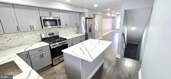 a kitchen with stainless steel appliances kitchen island granite countertop a stove a sink and a refrigerator