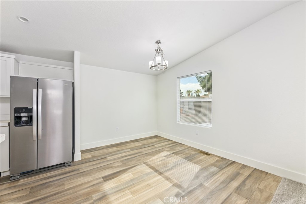 15252 Seneca Road, Unit 167 Victorville, CA 92392 - Photo 4 of 7 a view of an empty room with wooden floor and a window