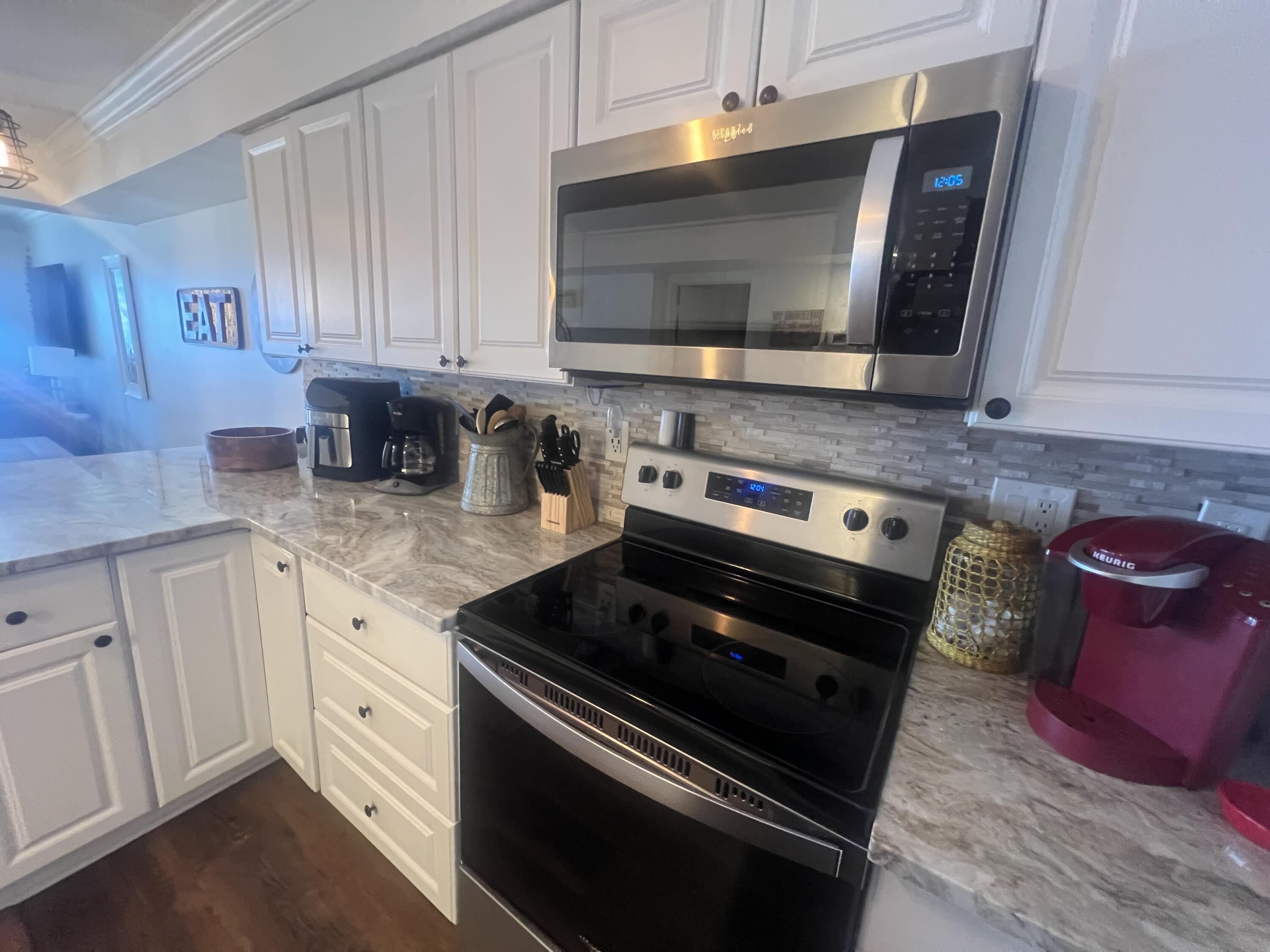 23223 Front Beach Road, Unit 703 Panama City Beach, FL 32413 - Photo 14 of 34 a kitchen with granite countertop a stove and a microwave