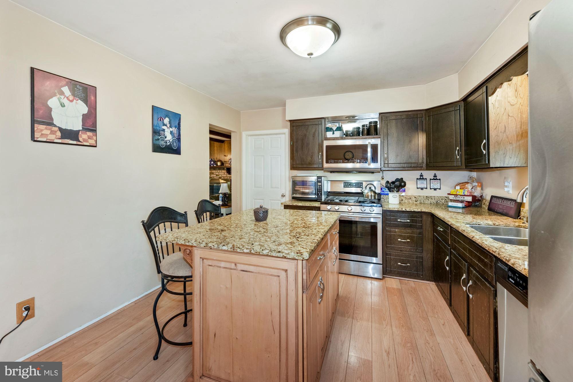 374 Holly Road Marlton, NJ 08053 - Photo 7 of 28 a kitchen with stainless steel appliances granite countertop a stove top oven a sink a dining table and chairs with wooden floor
