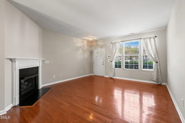a view of empty room with wooden floor and fireplace