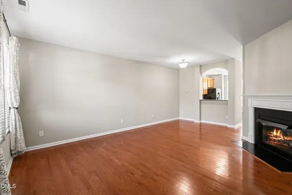 a view of empty room with wooden floor and fireplace