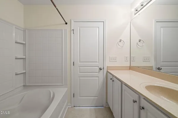 a bathroom with a tub sink vanity granite and shower