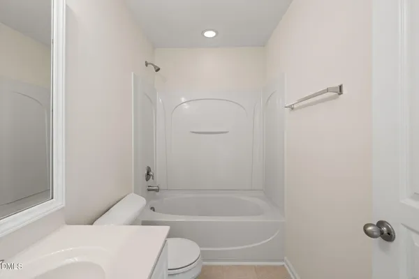 a bathroom with a granite countertop bathtub shower sink vanity and toilet