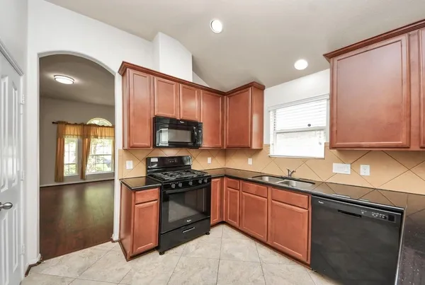 a kitchen with stainless steel appliances granite countertop a stove a sink and a microwave