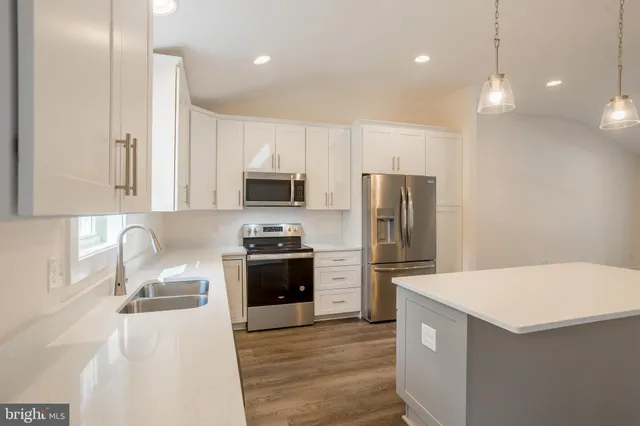 a kitchen with granite countertop a refrigerator stove and sink