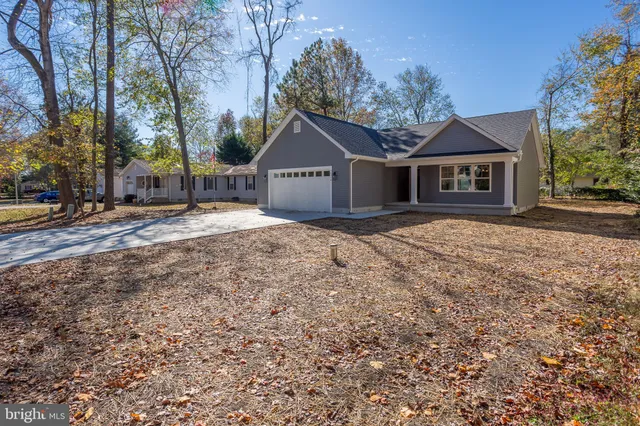 a front view of a house with a yard and large tree