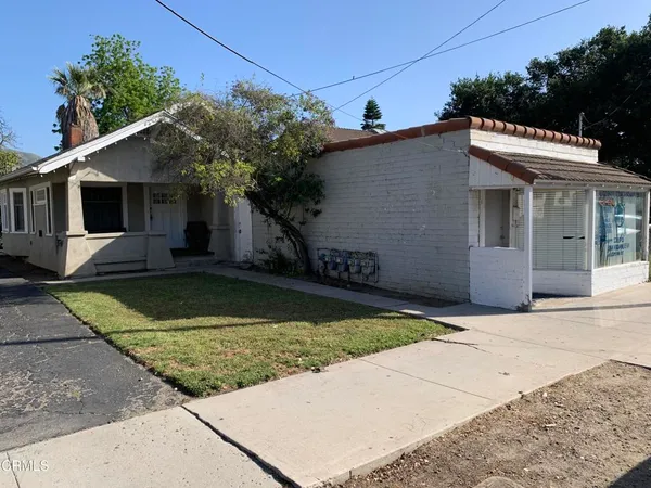 a view of a house with a small yard plants and a large tree