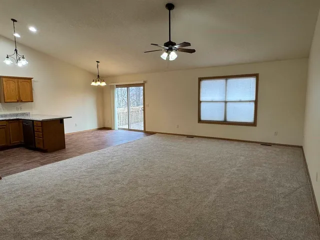 an empty room with chandelier fan and windows
