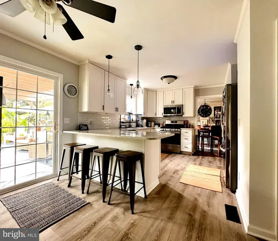 a open kitchen with granite countertop a stove top oven a sink a dining table and chairs with wooden floor