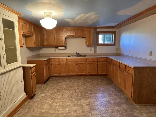 a large kitchen with a sink and dishwasher a oven with wooden cabinets