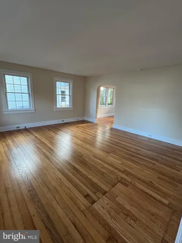 an empty room with wooden floor and window