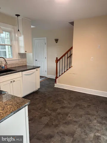 a large white kitchen with granite countertop a sink and dishwasher a stove with wooden floor