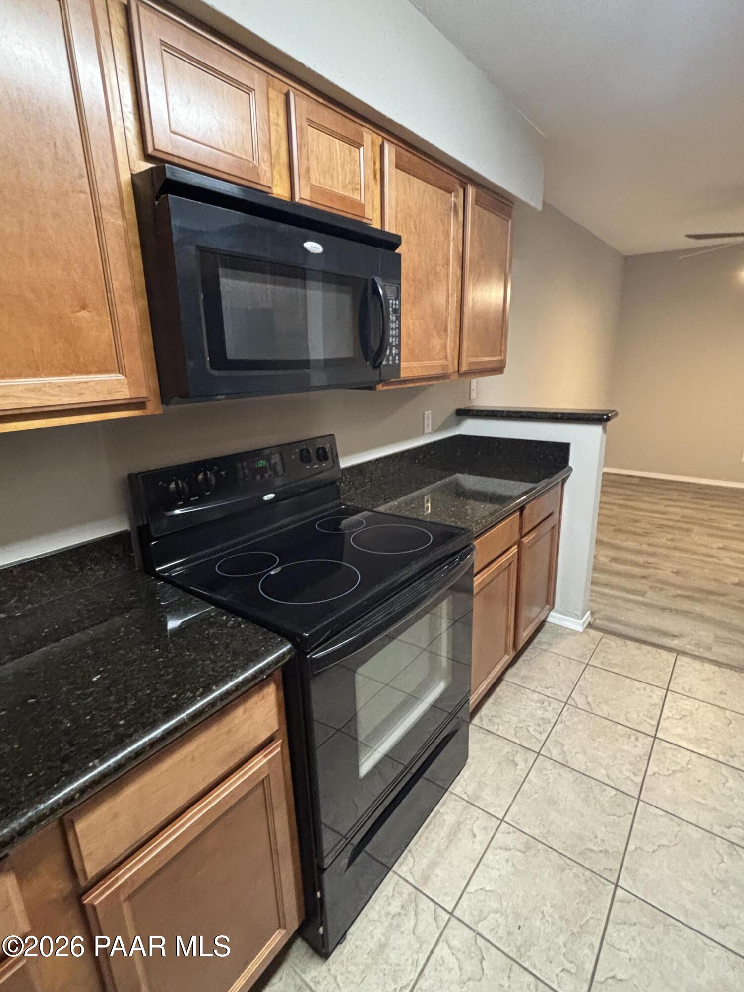 8787 East Mountain View Road, Unit 1082 Scottsdale, AZ 85258 - Photo 10 of 46 a kitchen with granite countertop a stove top oven cabinetry a sink and a microwave