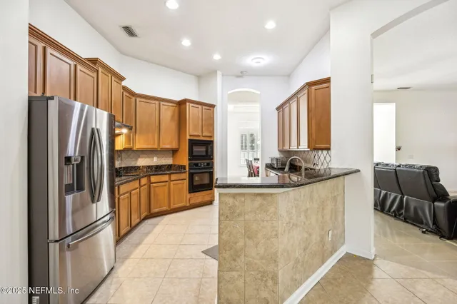 a kitchen with granite countertop a refrigerator and a stove top oven