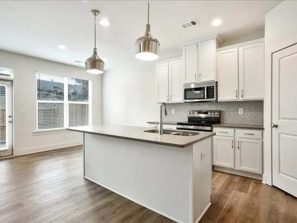a kitchen with stainless steel appliances granite countertop a sink a stove a microwave a center island and a window