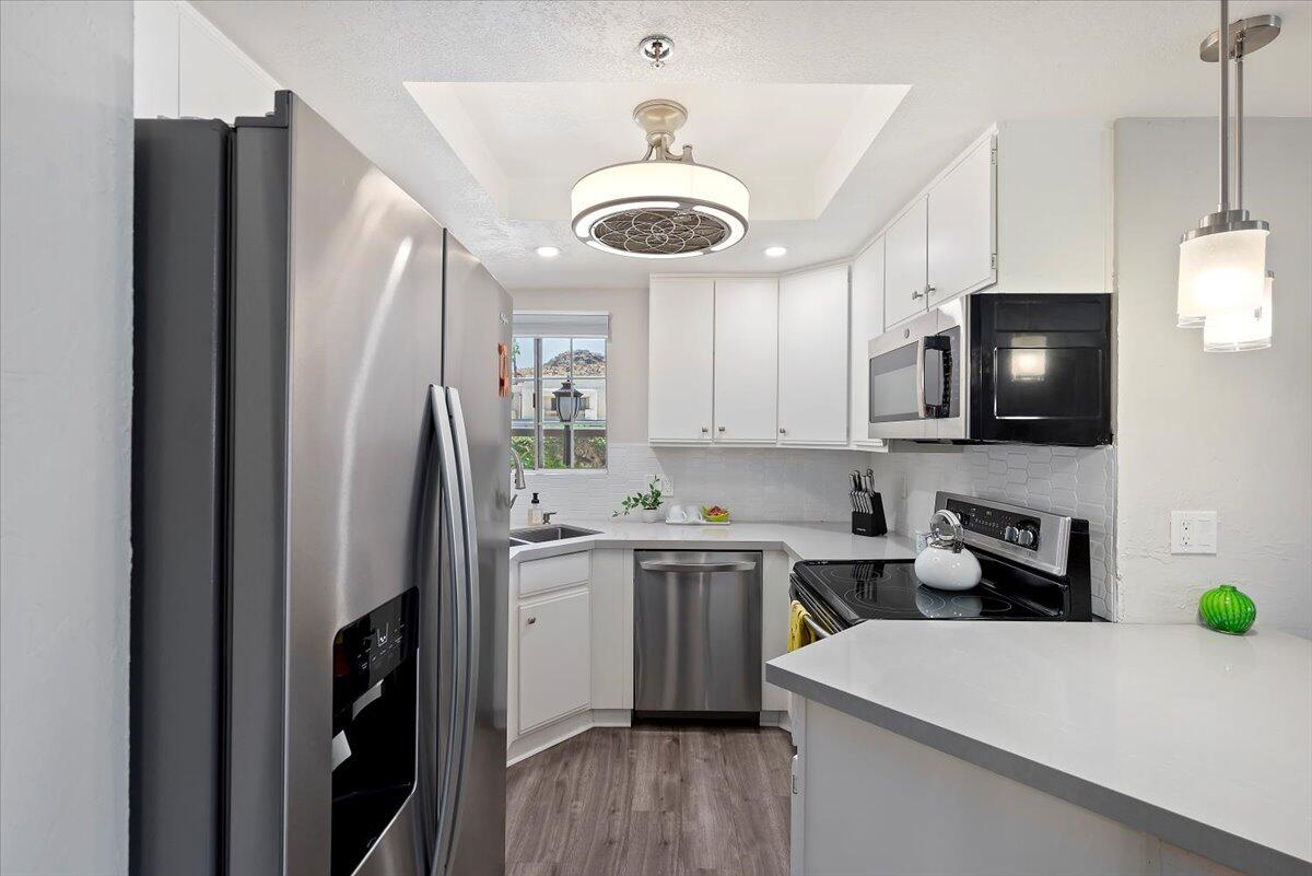 2700 Lawrence Crossley Road, Unit 10 Palm Springs, CA 92264 - Photo 8 of 15 a kitchen with stainless steel appliances a refrigerator a sink a stove a microwave and wooden cabinets